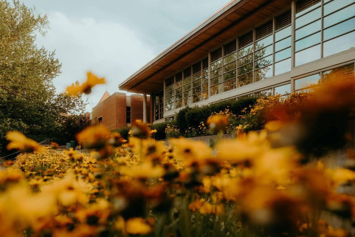 what is outdoor garden in school showing a weathered bronze heron statue beside raised vegetable beds and student-placed mosaic stepping stones in a sunlit elementary courtyard